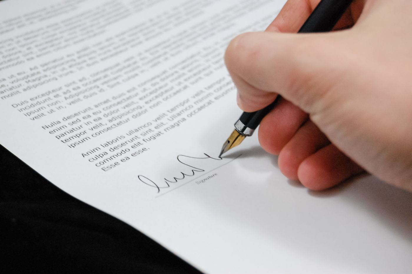 Close-up of a hand signing a document with a fountain pen